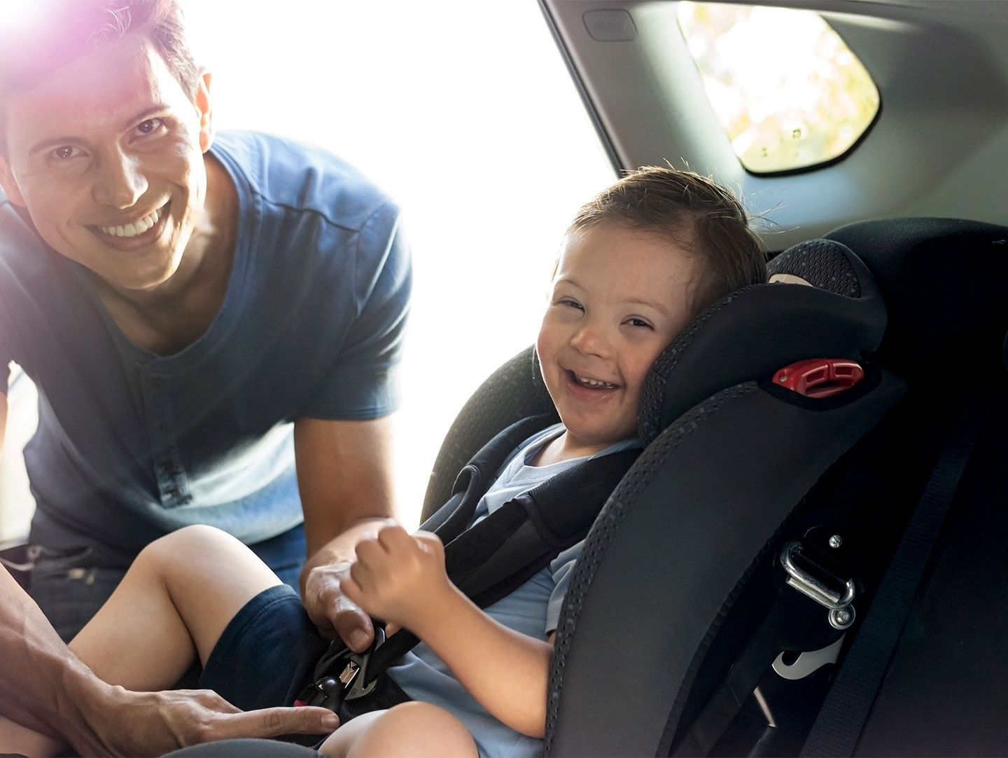 father clipping seat belt into place for daughter in a car