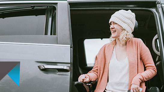 woman wearing a beanie in a wheelchair leaving a van